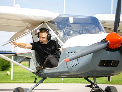 A pilot wearing a RayTalk aviation headset while operating a private aircraft in the cockpit